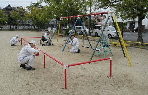 Employee volunteers painting a school swing set